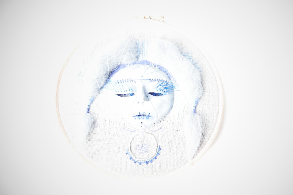 Hand embroidered face disappearing in light